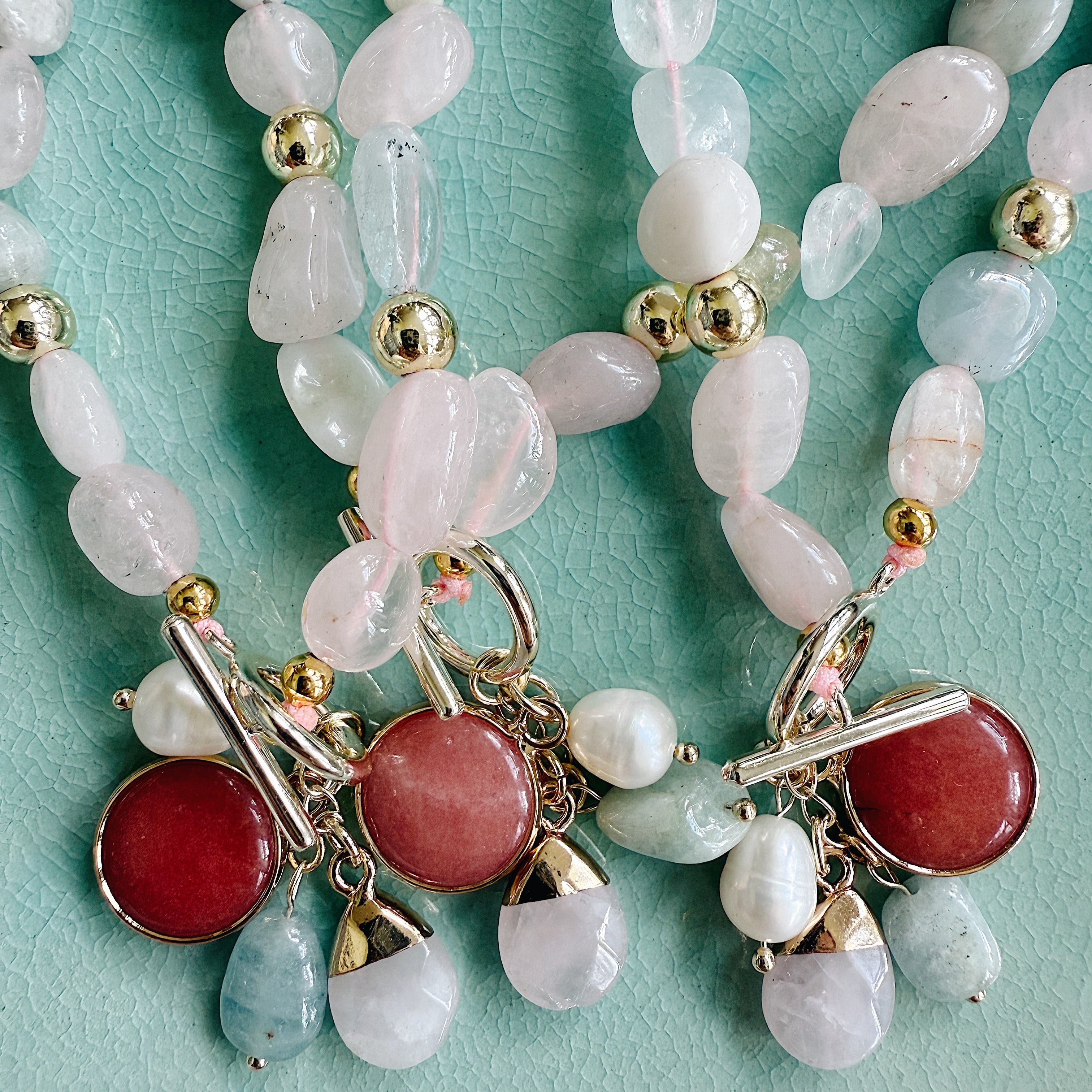 Morganite and freshwater pearl necklace on gold chain, close-up of soft pink and pearl tones styled against skin.