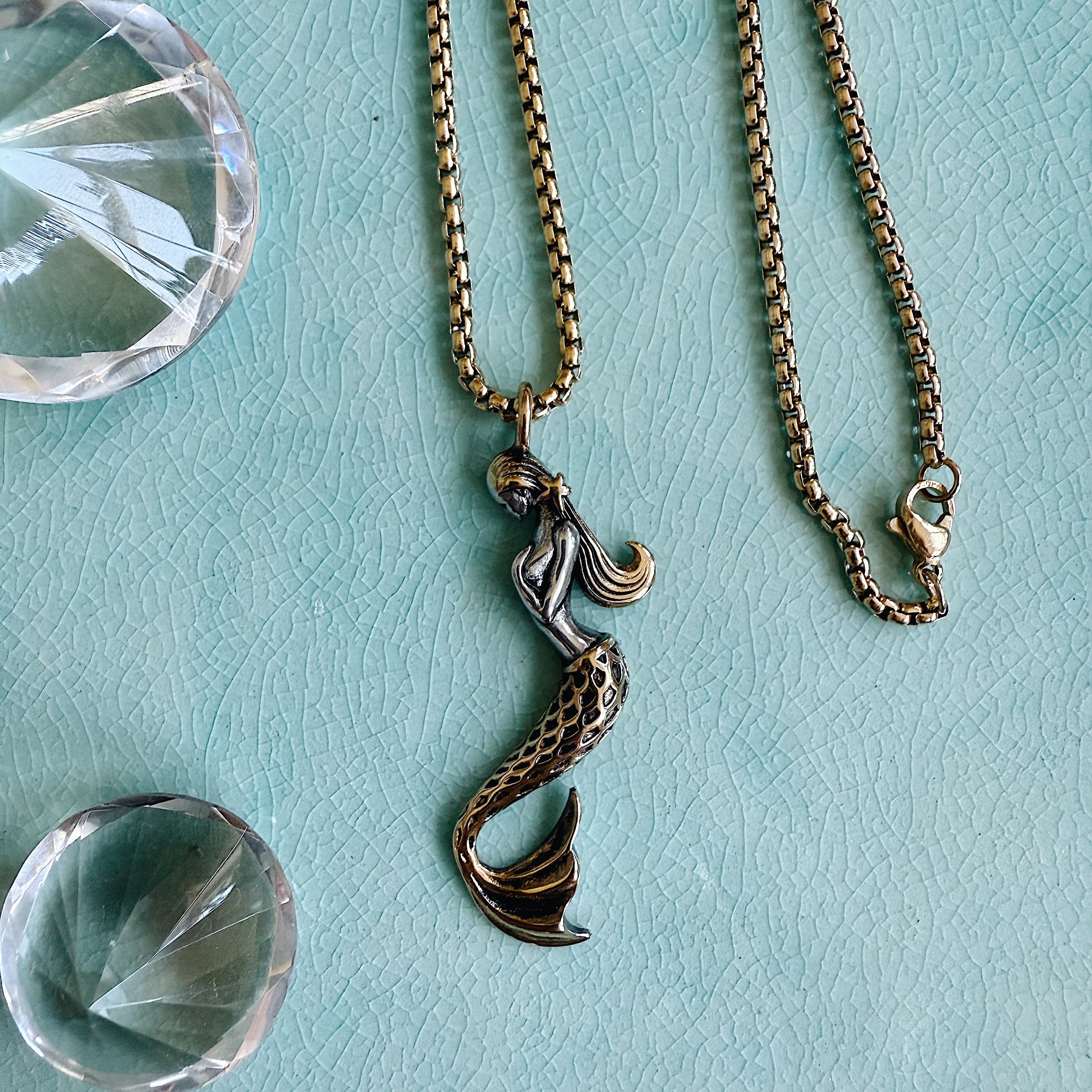 The Soleil Necklace with a detailed mermaid charm on a gold stainless steel chain, styled for layering or everyday wear.