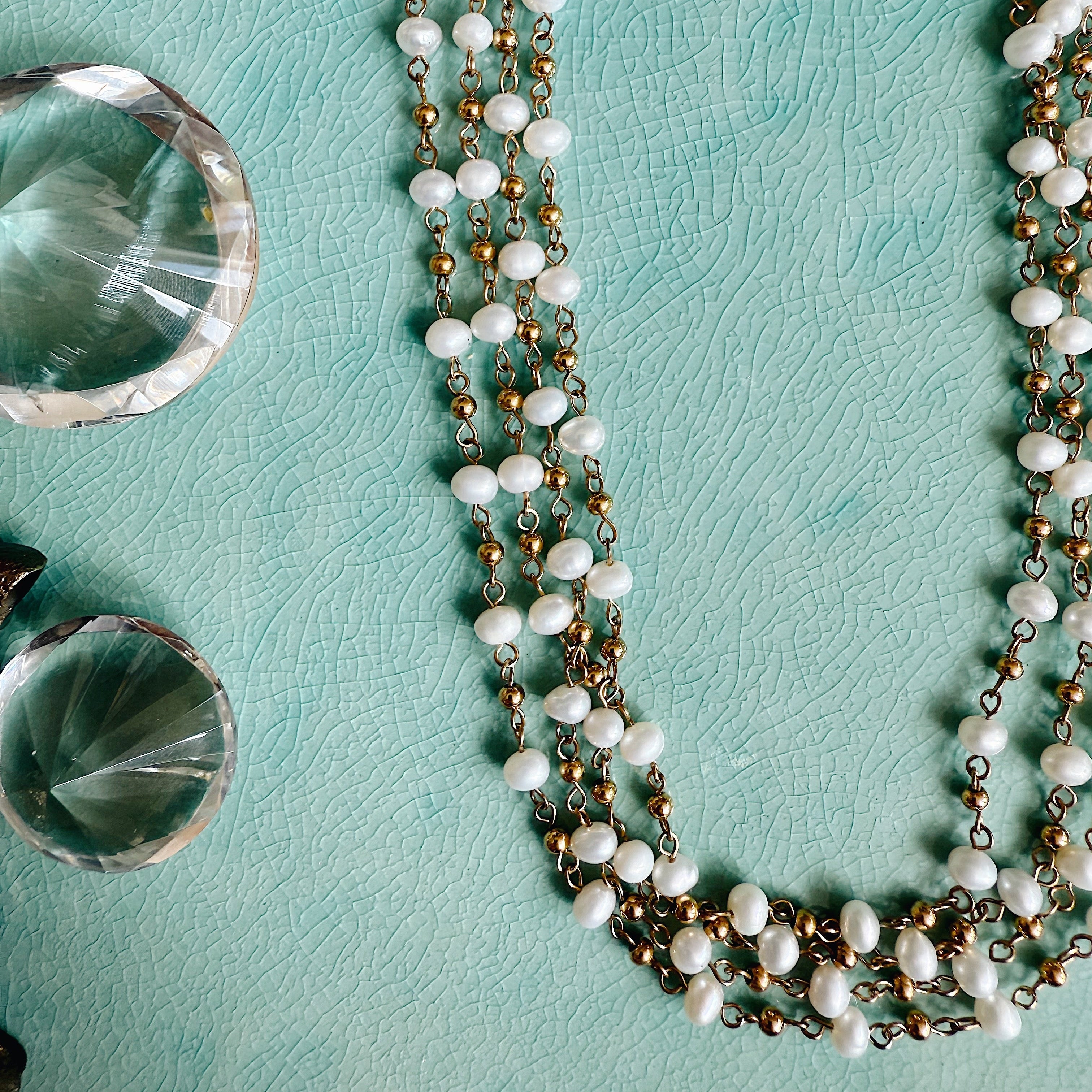 Rosary-style gold necklace featuring spaced freshwater pearls on a 16-inch chain with 2-inch extender, styled on neck or flatlay.