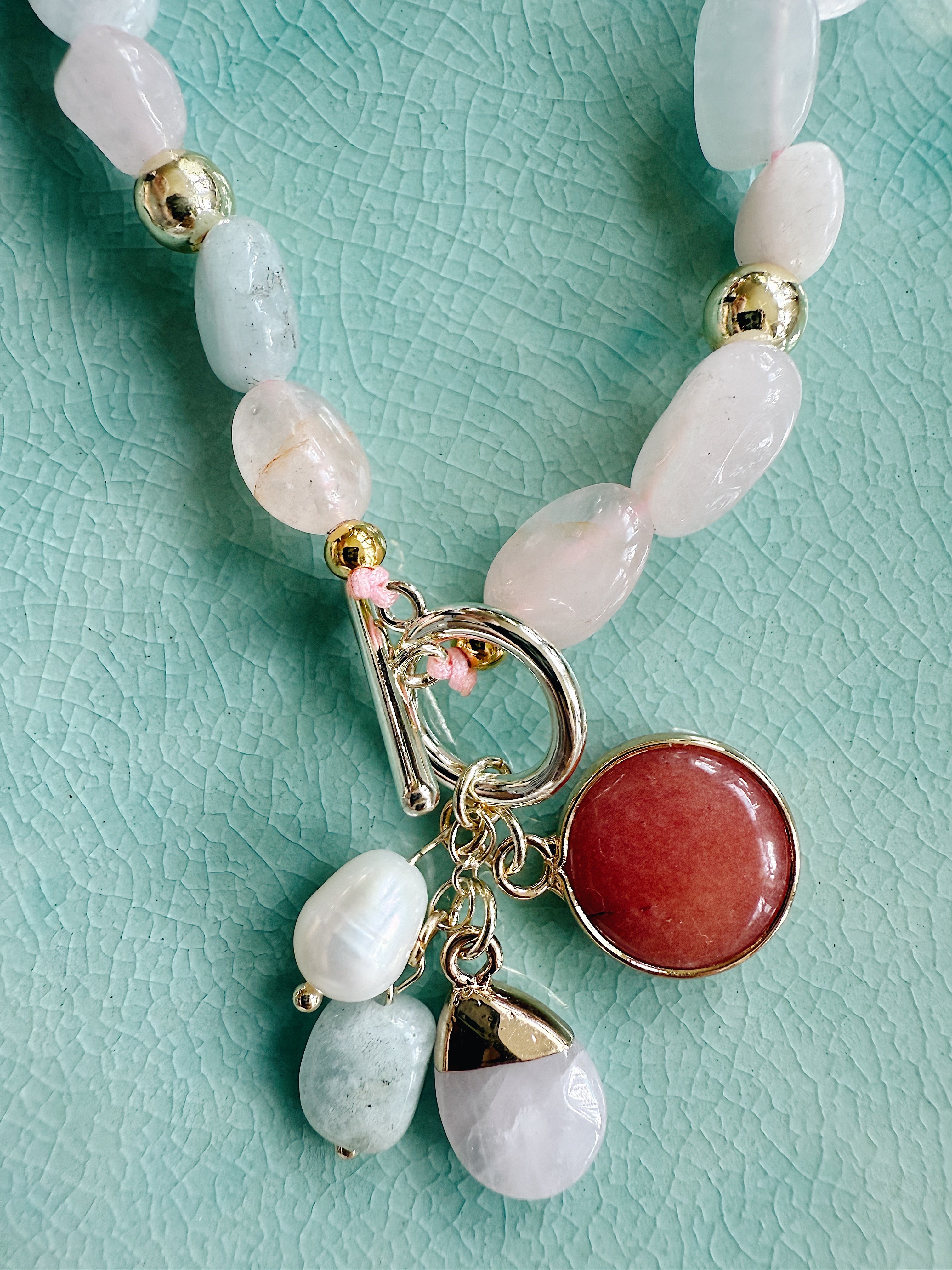 Morganite and freshwater pearl necklace on gold chain, close-up of soft pink and pearl tones styled against skin.