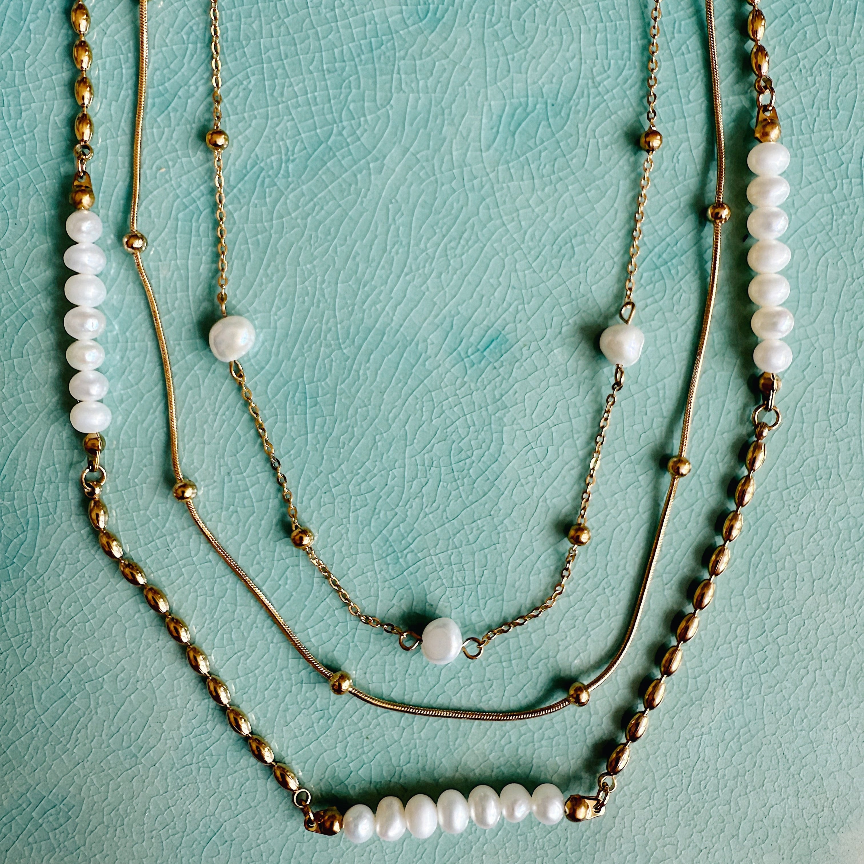 Layered gold and freshwater pearl necklace set featuring three 16-inch chains with 2-inch extenders, styled flatlay or on model.