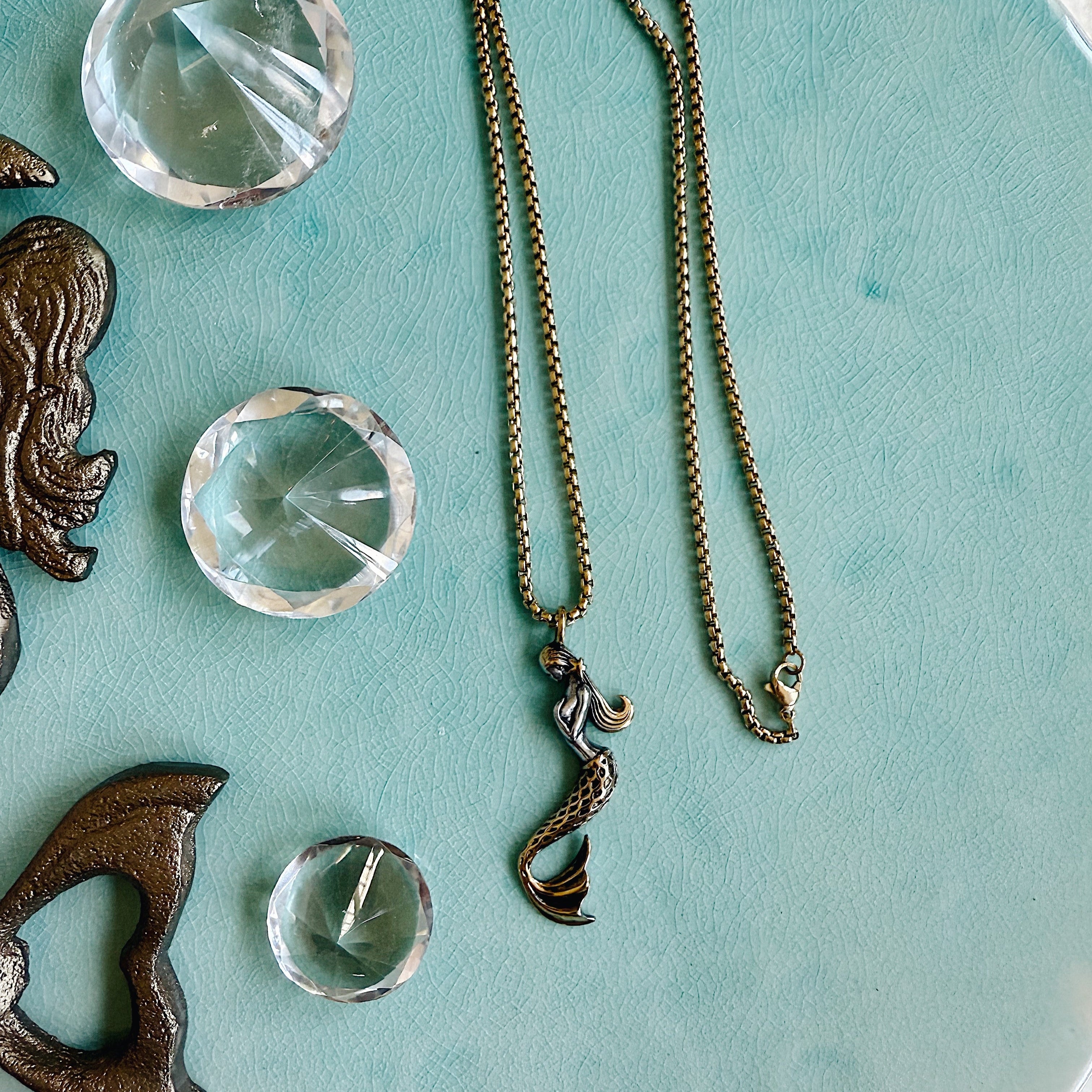 The Soleil Necklace with a detailed mermaid charm on a gold stainless steel chain, styled for layering or everyday wear.